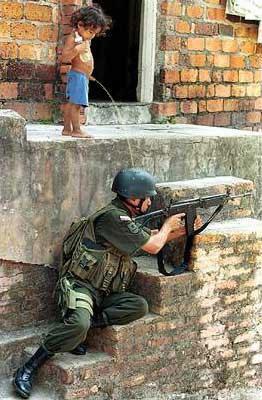 Смешной мальчик писает на каску солдата пока он стреляет в противников